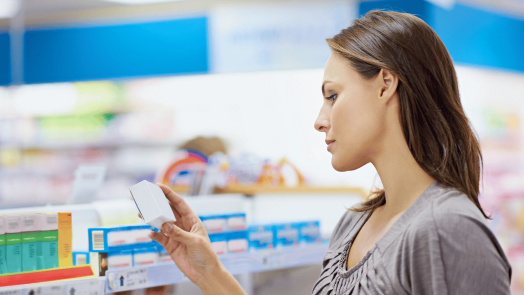 Woman reading medication label in pharmacy aisle, evaluating over-the-counter drug options—representing safe medication use during Suboxone treatment