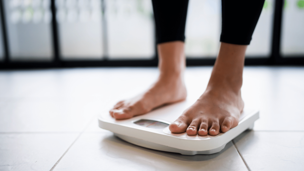 Close-up of person standing barefoot on a digital bathroom scale, tracking weight loss progress on GLP-1 medication like Mounjaro, Wegovy, or Ozempic