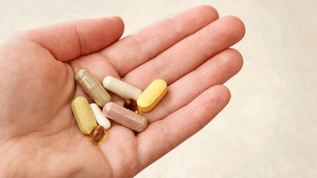 Closeup of a hand holding various vitamins and health supplements