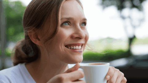 Smiling woman enjoying a cup of coffee outdoors, symbolizing peace, stability, and recovery during long-term Suboxone treatment
