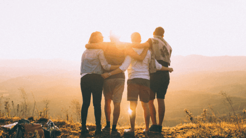 Group of friends or family members standing together at sunset, symbolizing support and unity in addiction recovery