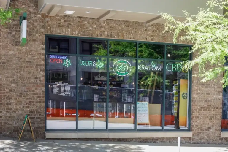 storefront-with-neon-signs-advertising-Kratom-Delta-8-CBD-and-Medical-Cannabis-products-in-a-brick-building