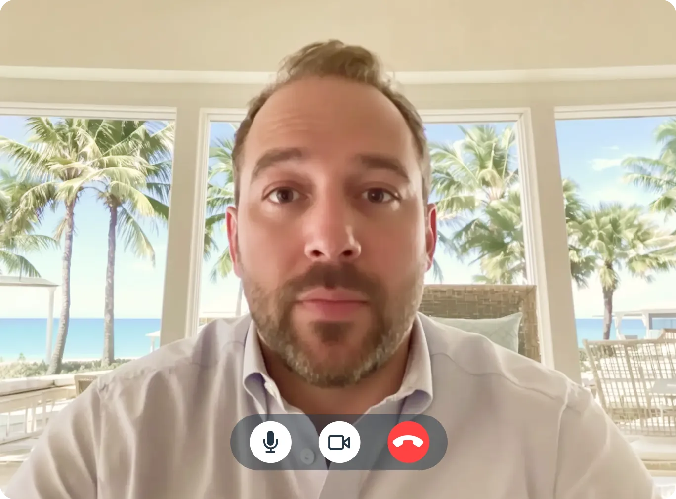 Man on a video call with palm trees and ocean view in background, California coastal setting