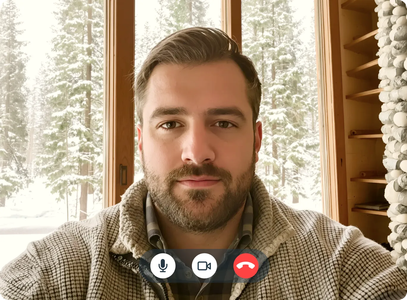 Man on a telehealth video call in a Colorado mountain cabin with snow-covered pine trees visible through the window