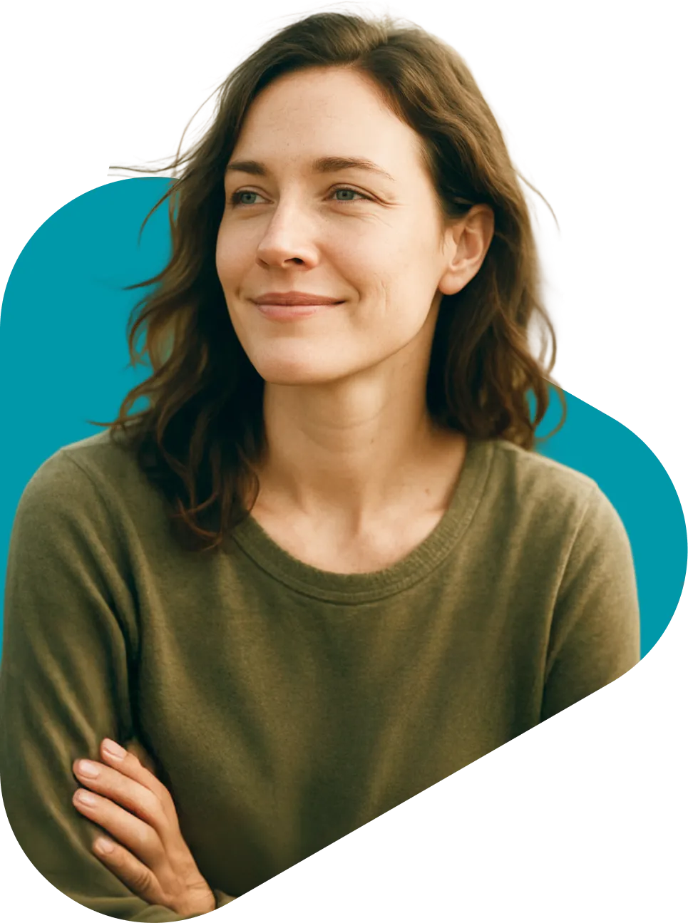 Smiling young woman with brown wavy hair wearing an olive green sweater, arms crossed, against a teal background