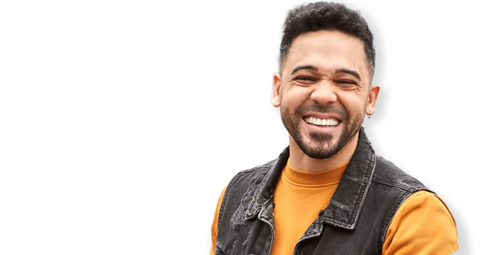 Happy young man smiling confidently after weight loss, wearing an orange shirt and denim vest