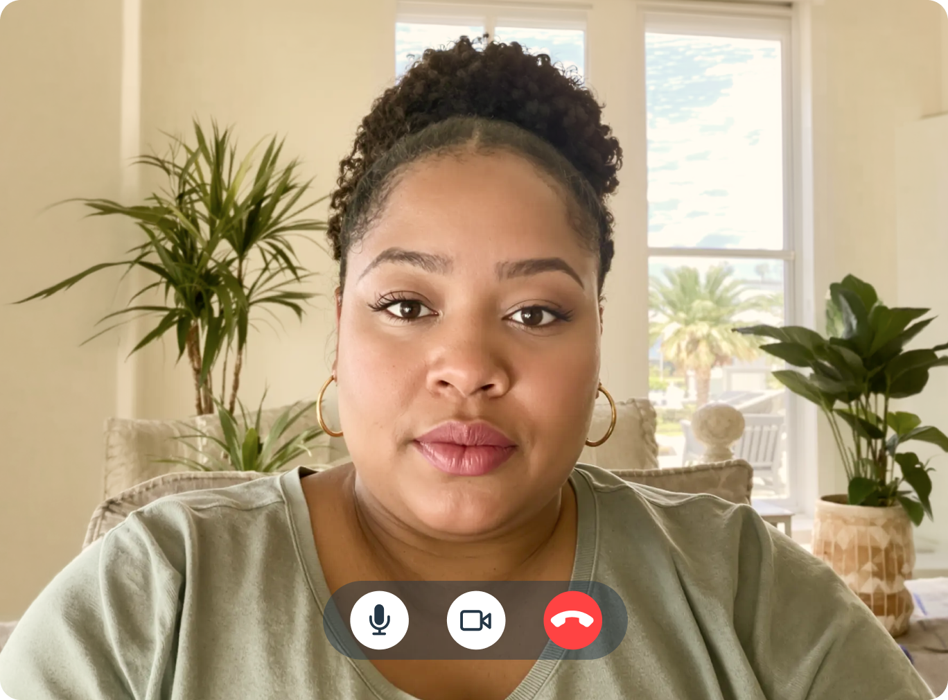 Woman on a telehealth video call at home, wearing gold hoop earrings and a green shirt