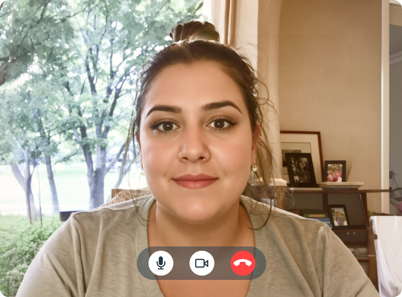 Woman on a telehealth video call at home, with trees visible through a window in the background