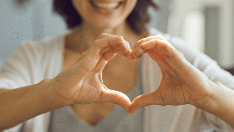 Smiling woman forming a heart shape with her hands to symbolize heart health and wellness from GLP-1 weight loss medications
