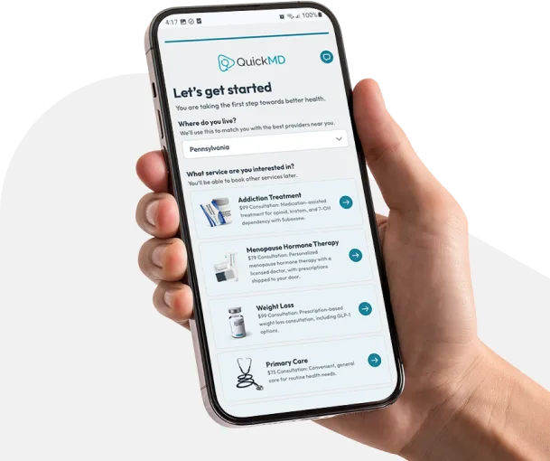 Hand holding a smartphone displaying the QuickMD app onboarding screen with telehealth service options including addiction treatment and weight loss.