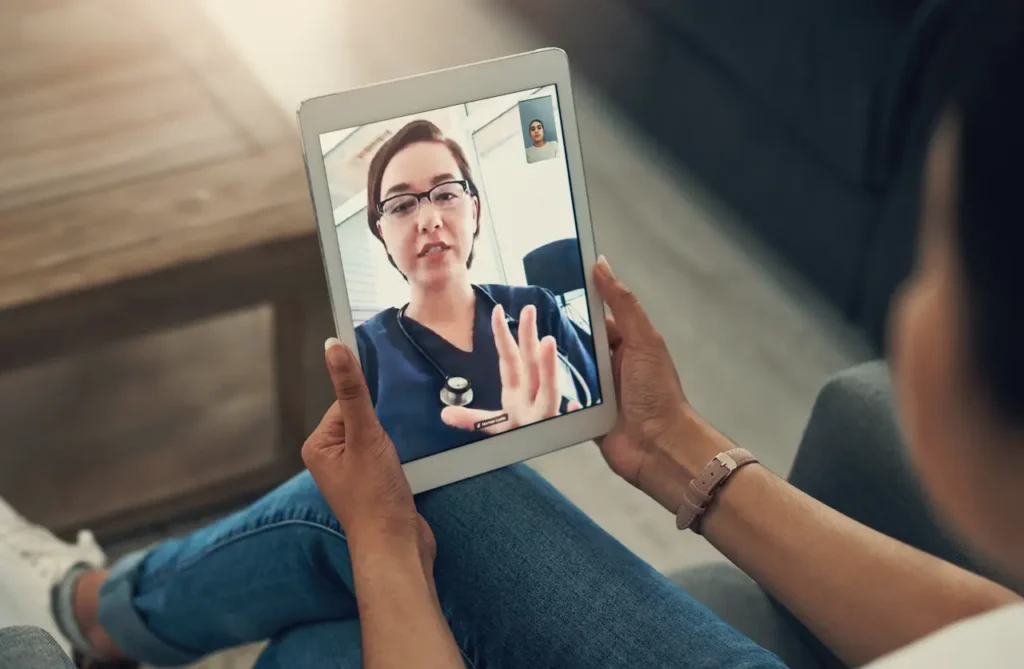 Person holding a tablet during a telehealth visit with a doctor, illustrating online urgent care for getting a doctor’s note.