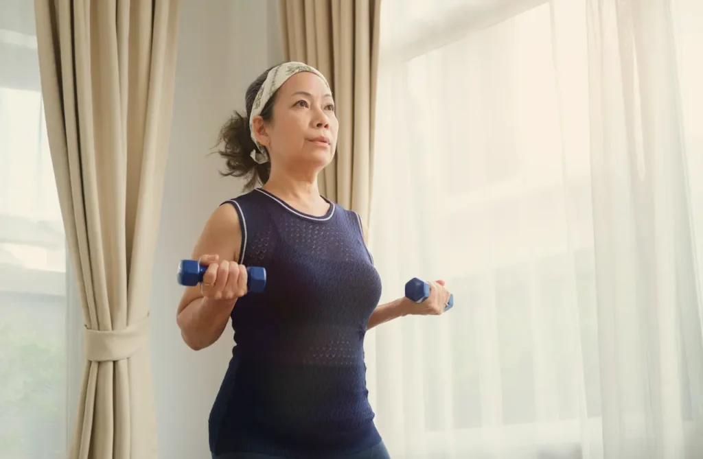 Woman exercising at home with dumbbells, illustrating healthy lifestyle changes during menopause.