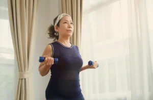 Woman exercising at home with dumbbells, illustrating healthy lifestyle changes during menopause.