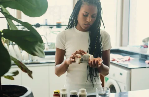 woman-in-kitchen-taking-supplements