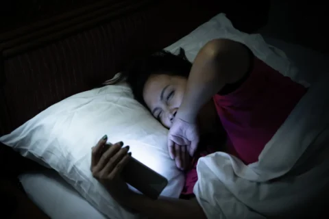 woman-lying-in-bed-awake-on-phone