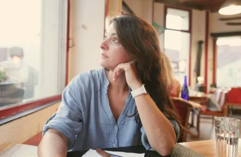 woman-staring-out-window-in-cafe-thinking